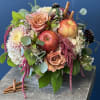 Mixed bouquet with roses, chrysanthemums, and apples on a stone pedestal