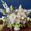 White floral arrangement in a white vase with roses, lilies, and chrysanthemums