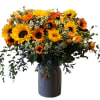 Bouquet of sunflowers and orange blooms in a dark vase