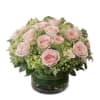 Pink roses arranged in a low glass vase with green hydrangeas