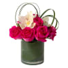 Short arrangement of hot pink roses and white orchids in a leaf-lined glass cylinder vase