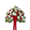 Tall red and white sympathy spray with roses, lilies, and mums accented by a large red ribbon bow.