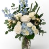 White roses and blue hydrangea with blue delphinium in a clear glass vase