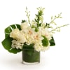 White floral arrangement in a green glass vase with orchids and roses