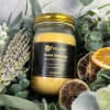 A candle in a glass jar surrounded by flowers, greenery, and dried citrus slices