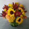 Bouquet of sunflowers, red blooms, and peach roses in a glass vase