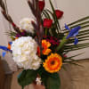 Mixed bouquet with red roses, white hydrangeas, and orange gerbera daisies in a vase