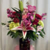 Mixed bouquet with lilies, roses, and pink flowers in a dark vase