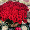 Large bouquet of red roses in a gold vase with white hydrangeas behind it
