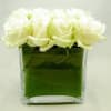 White roses in a square glass vase with green water