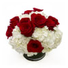 Red roses arranged with white hydrangeas in a low black vase