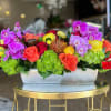 Rectangular flower arrangement with orchids, roses, and hydrangeas in a white container