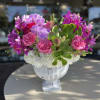 Pink orchids and roses arranged in a white pedestal vase