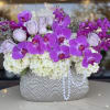 Purple orchids and pale roses in a silver textured vase