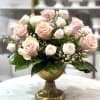 Pink and white roses arranged in a gold pedestal vase