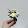 Two ivory-white roses sit close together in this compact boutonniere, surrounded by