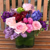 Mixed bouquet of pink, purple, and red flowers in a green vase