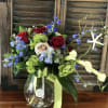 Bouquet of red and blush roses with blue flowers in a glass vase