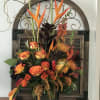 Orange and yellow floral arrangement in a dark vase with tall tropical blooms