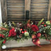 Long holiday centerpiece with red roses, pinecones, and a ribbon in a wooden box