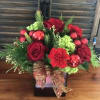 Red roses and carnations in a black vase with green accents and a gold ribbon