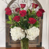 Red roses and white hydrangeas arranged in a clear glass vase