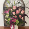 Pink roses and lilies arranged in a white vase with ribbon