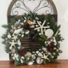Shell-covered evergreen wreath on a decorative metal and wood frame