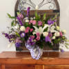 Mixed bouquet with white lilies, pink roses, and purple flowers in a ribbon-tied vase