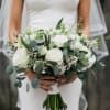 Bride holding a white bouquet with green foliage