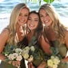 Three women holding small bouquets on a beach