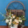 White roses and sunflowers in a white vase with greenery