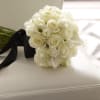 White rose bouquet with black ribbon on a white chair