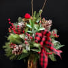 Holiday arrangement with pinecones, berries, and a red plaid ribbon in a glass vase
