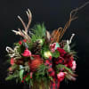Holiday floral arrangement in a glass vase with pinecones, berries, and plaid ribbon