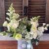 White floral arrangement in a silver tin with a blue ribbon