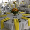 Round banquet tables with yellow napkins and floral centerpieces