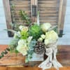 Succulent and white floral arrangement in a small box with pinecones and ribbon