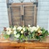 White roses and greenery arranged in a rectangular wooden box with gold accents