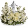 White floral arrangement with a small statue of Jesus in the center