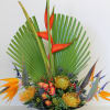 Tall tropical arrangement with orange and yellow flowers in a black shallow bowl.