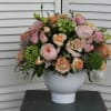 Low white vase of pink and peach roses and carnations with green hydrangea accents