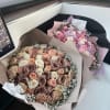 Two bouquets of pastel roses wrapped in paper on a car seat