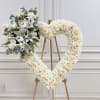 Heart-shaped floral wreath on an easel with white roses and lilies