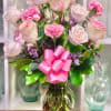Pink roses and carnations in a glass vase with a pink ribbon