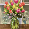 Mixed tulips in pink, coral, and yellow arranged in a glass vase