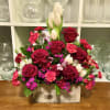 Mixed bouquet of red roses, pink carnations, and white tulips in a rectangular vase