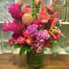 A beautiful warm arrangement filled with fresh cut roses, tropical flowers and