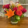Mixed bouquet of roses, lilies, and a gerbera daisy in a glass vase