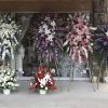 Large standing floral sprays in white, purple, pink, and red outside a storefront